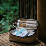 Open brown travel case with toiletries on a wooden surface outdoors