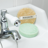 Two sponges on a sink with a faucet in the background