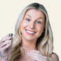 Woman holding a hair extension tool against a beige background