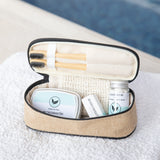 Open travel case with skincare products and brushes on a textured surface.