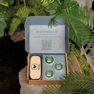 Green-themed product set with 'MyGreenRoutine' branding, including a travel case and three small containers, surrounded by greenery.