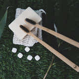 Two bamboo toothbrushes on a grassy surface with a white soap bar and small white stones.