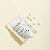 Package of natural toothpaste tablets with white capsules on a beige background