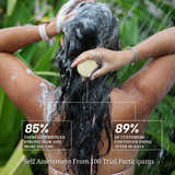 Person washing hair with a bar of soap outdoors, surrounded by greenery.