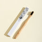 Bamboo toothbrush with black bristles and a leaf patterned handle on a beige background